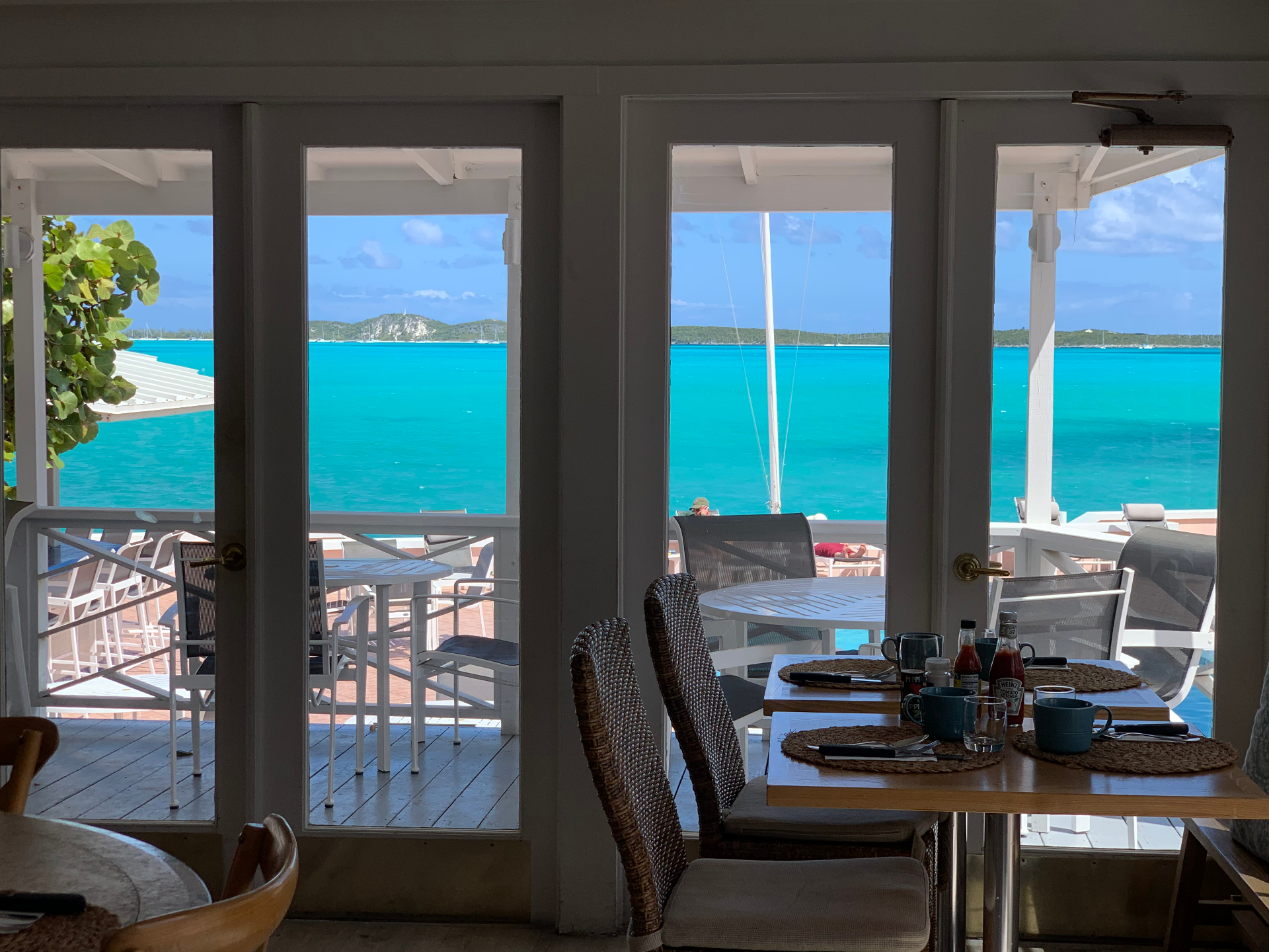 Breakfast tables framed by French doors opening to turquoise Bahamian sea
