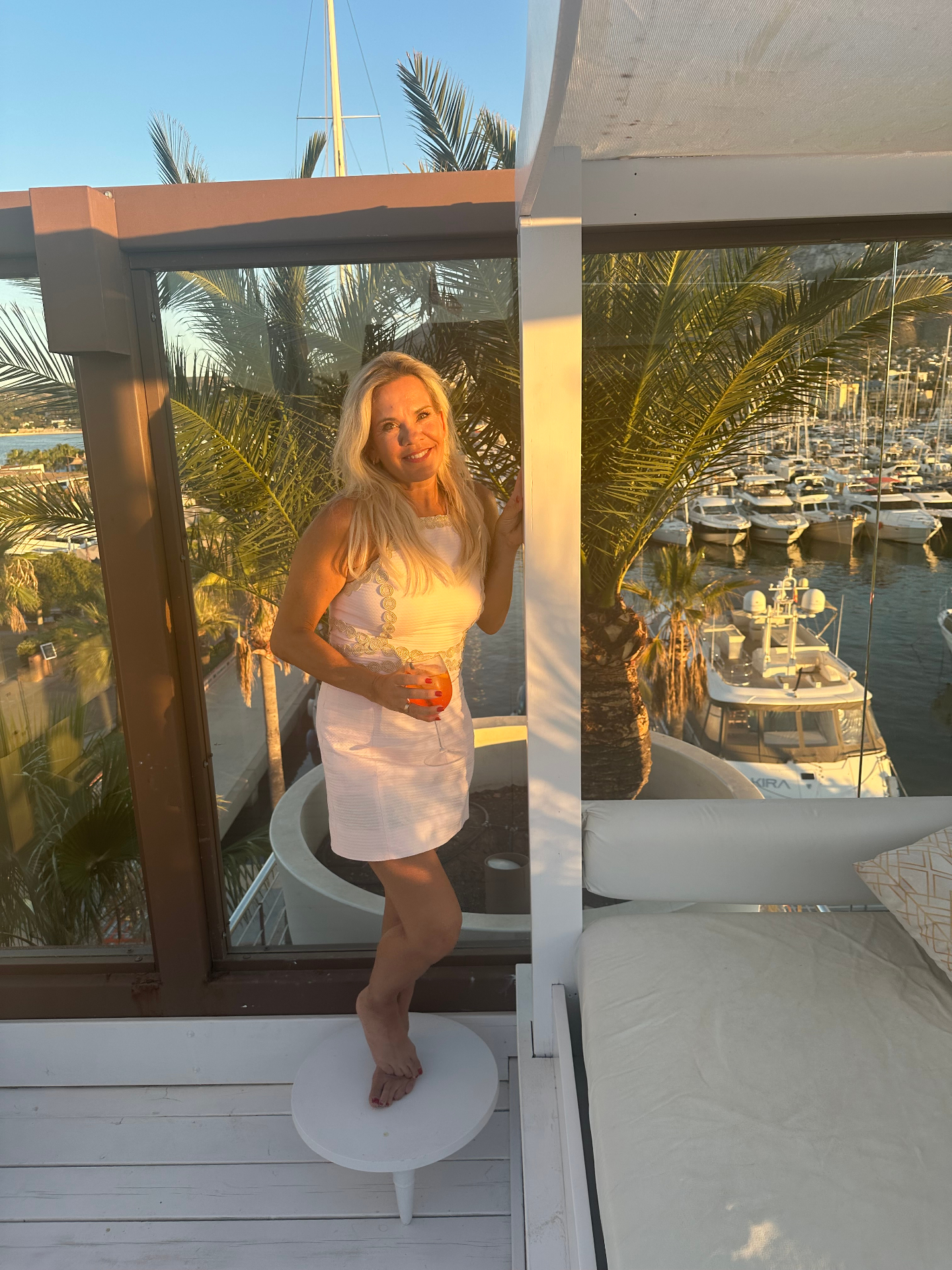 Linda in a white dress on a marina terrace at golden hour
